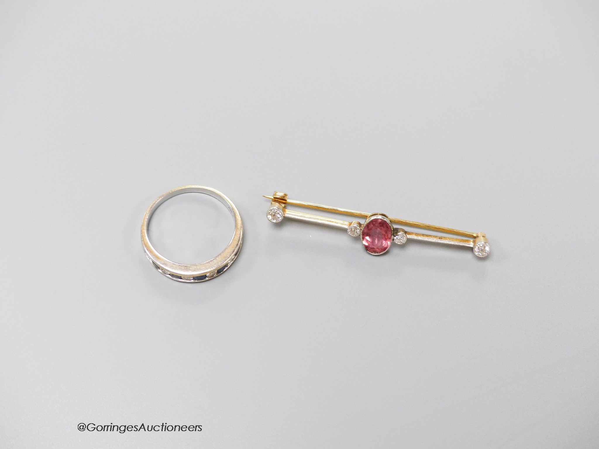 An early 20th century, yellow metal, pink tourmaline and four stone diamond set bar brooch, 47mm, gross 2.7 grams and and 18ct white gold, channel set sapphire and diamond set half eternity ring, size Q, gross 3.9 grams.